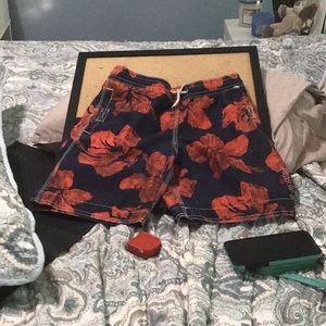 Kids swim shorts with 8” inseam, vibrant orange flowers on a blue background.